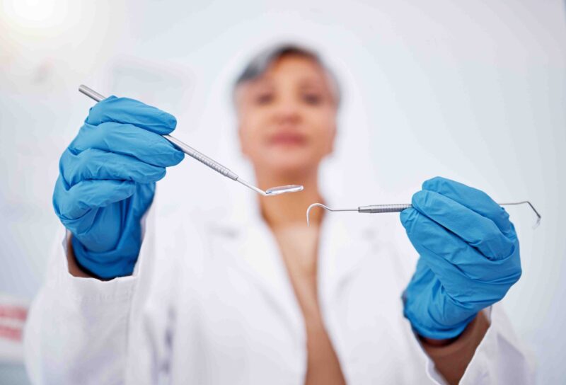 Dentist wearing gloves and holding dental tools during a dental care examination
